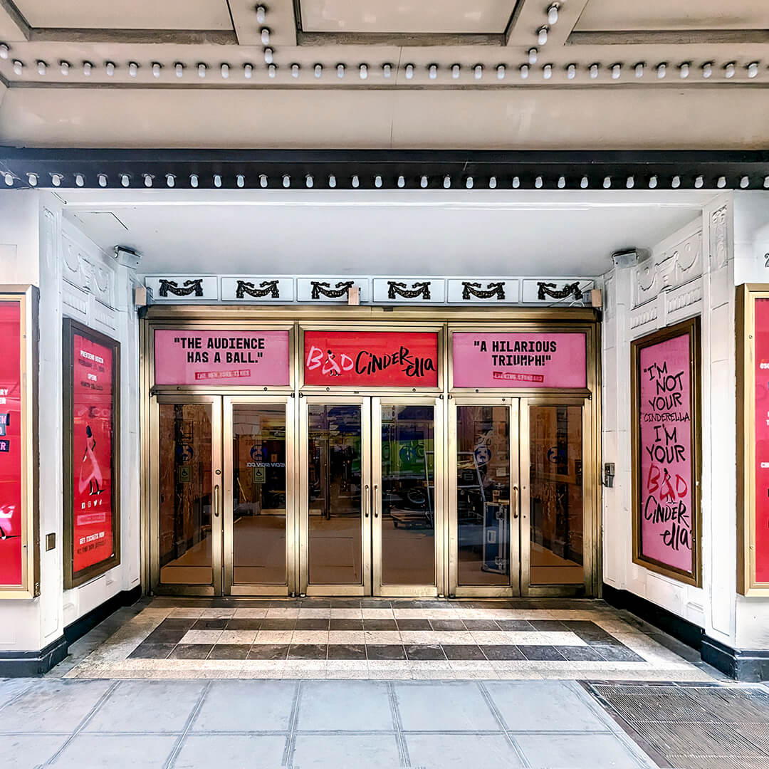 Theater entrance decorated with posters and slogans for the Bad Cinderella musical.