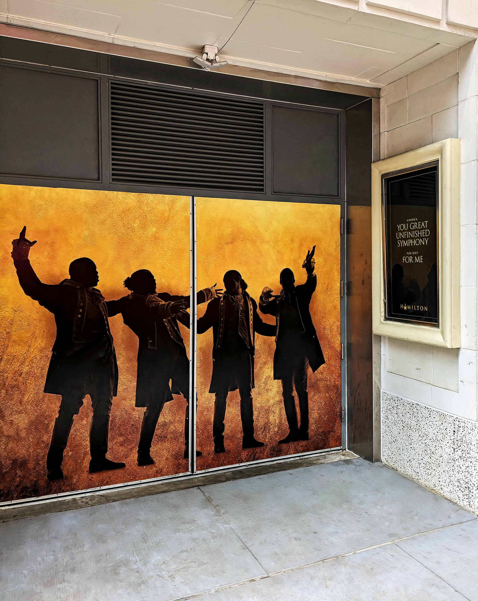 Entrée de théâtre avec affiches et silhouettes d’acteurs de la comédie musicale Hamilton.