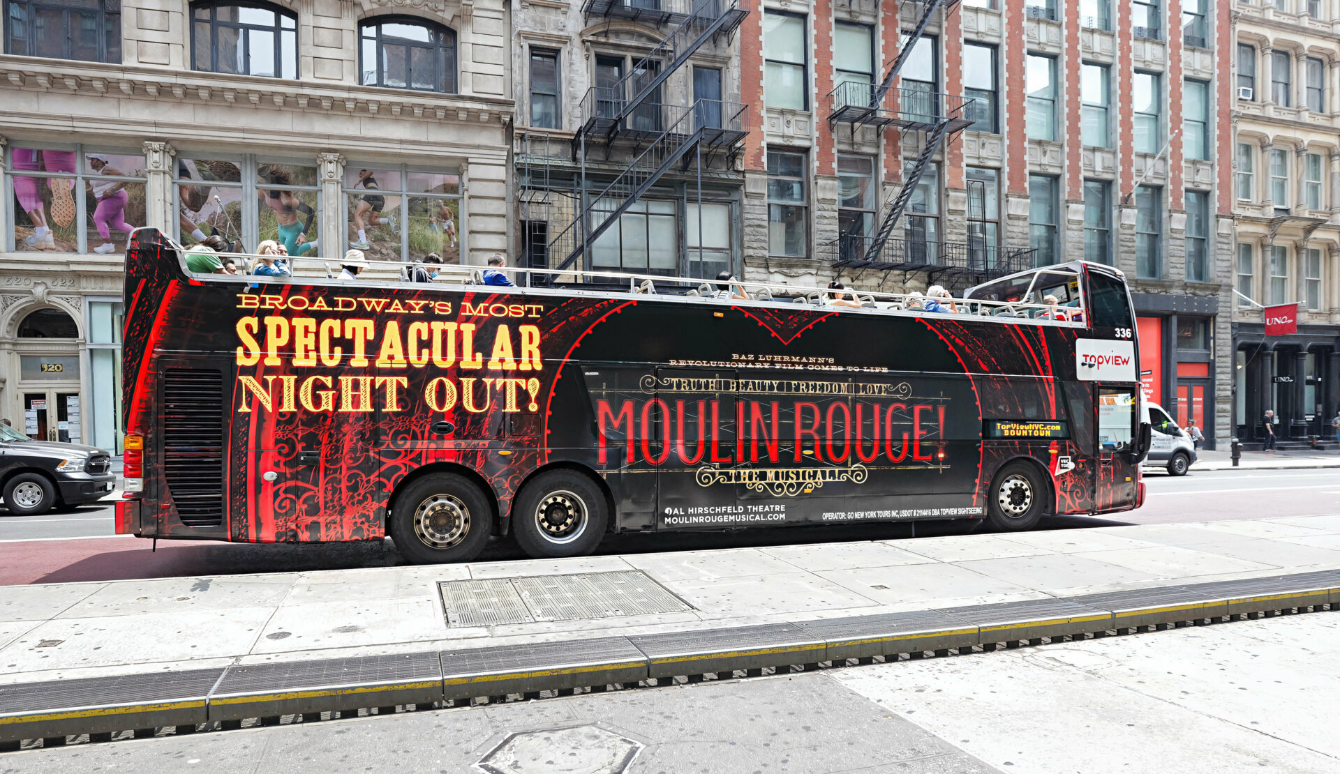 Autobus habillé de publicités Moulin Rouge à New York, annonçant une soirée spectaculaire.