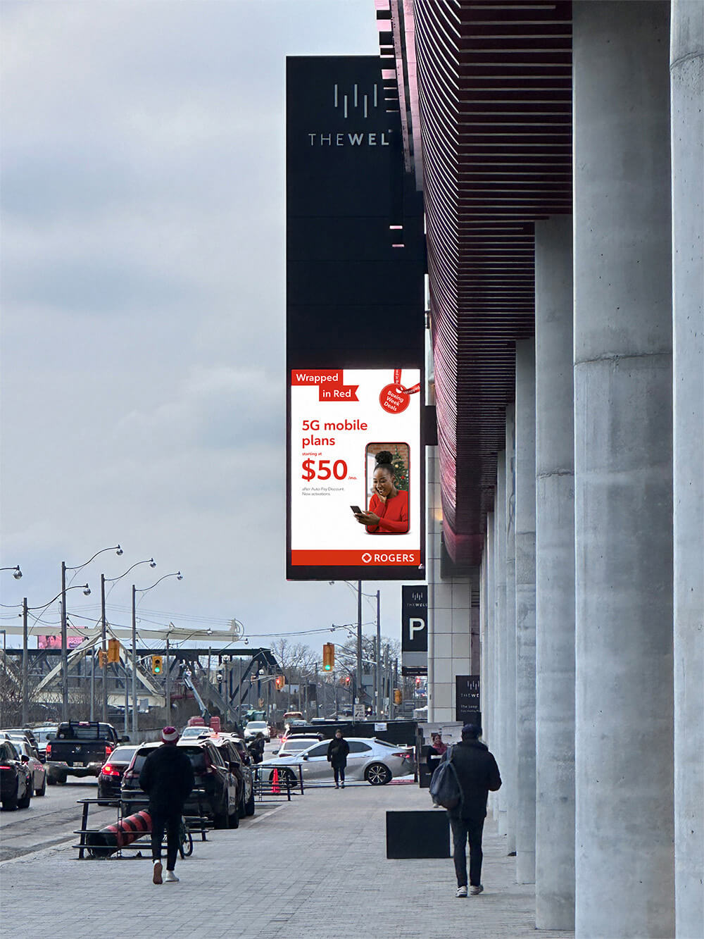 Vertical Rogers "Wrapped in red" digital billboard ad displayed on a city street.