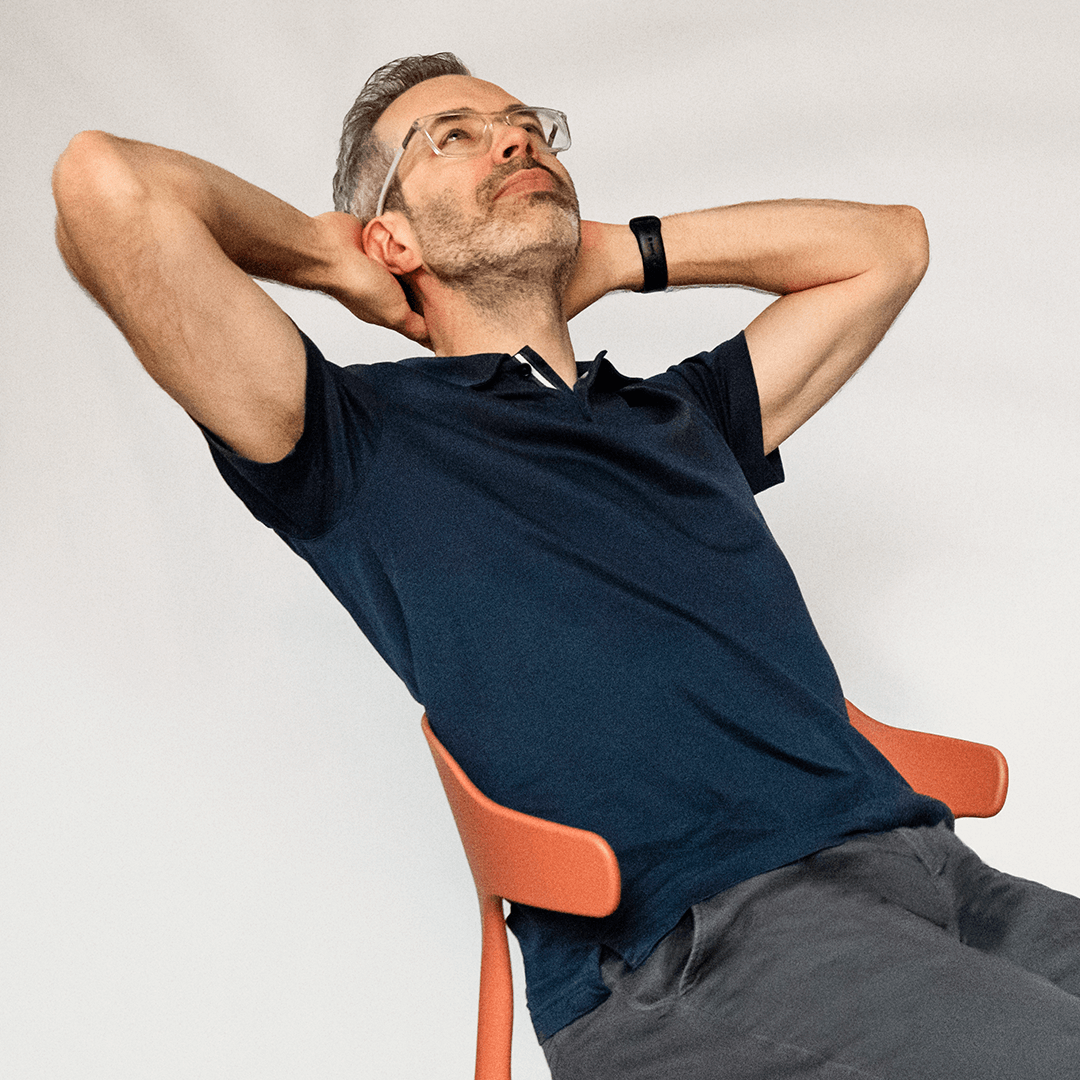 Fabien Castagnier leaning back in an orange chair with hands behind his head, looking relaxed.