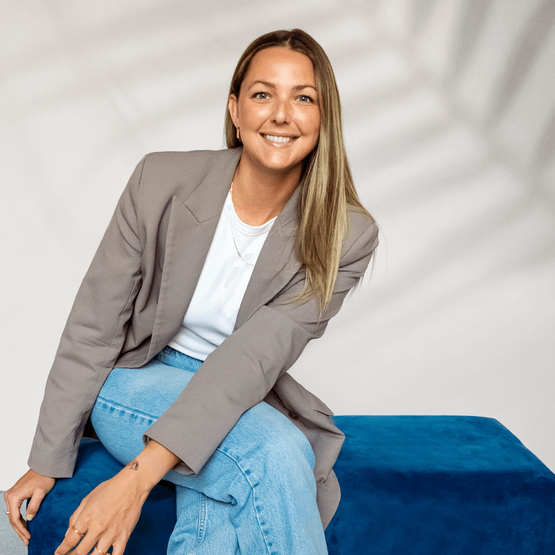 Stéphanie Gendron sitting in a rectangle blue pouf smiling.