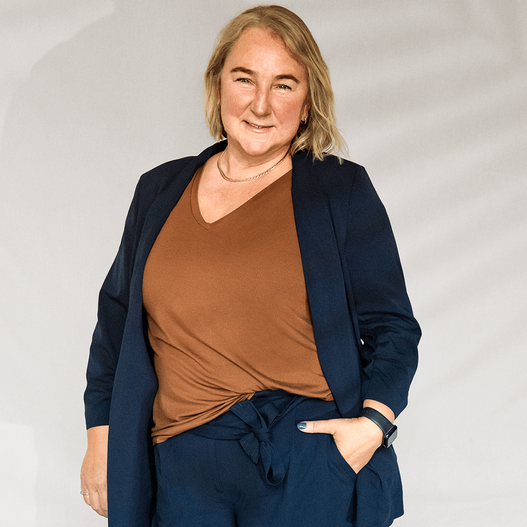 Sue Thoms smiling with her left hand in her pocket.