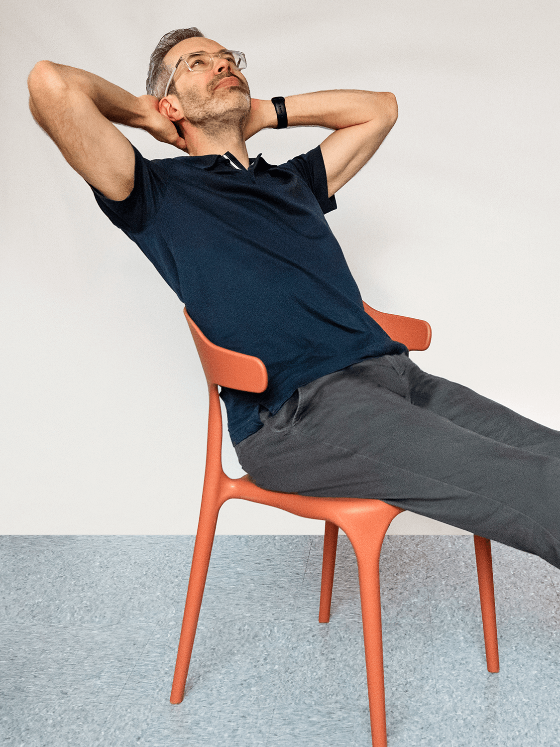 Fabien Castagnier leaning back in an orange chair with hands behind his head, looking relaxed.
