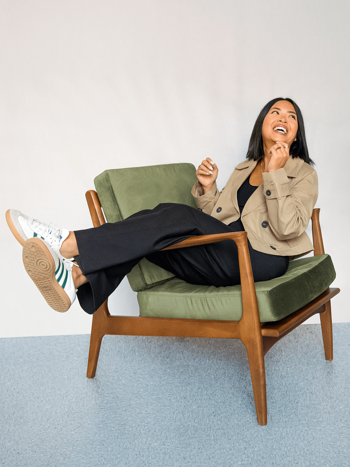 Phu Pham sitting and laughing in a green cushioned armchair.