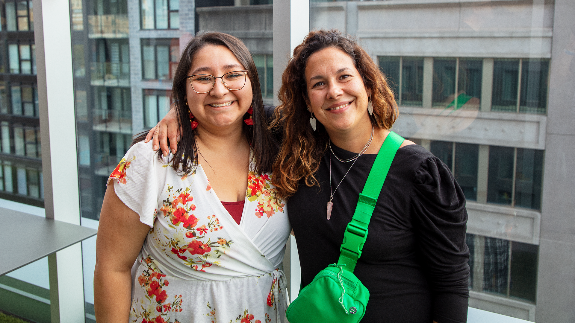 Two smiling colleagues posing side by side on a terrace in Montreal with cityscape in the background