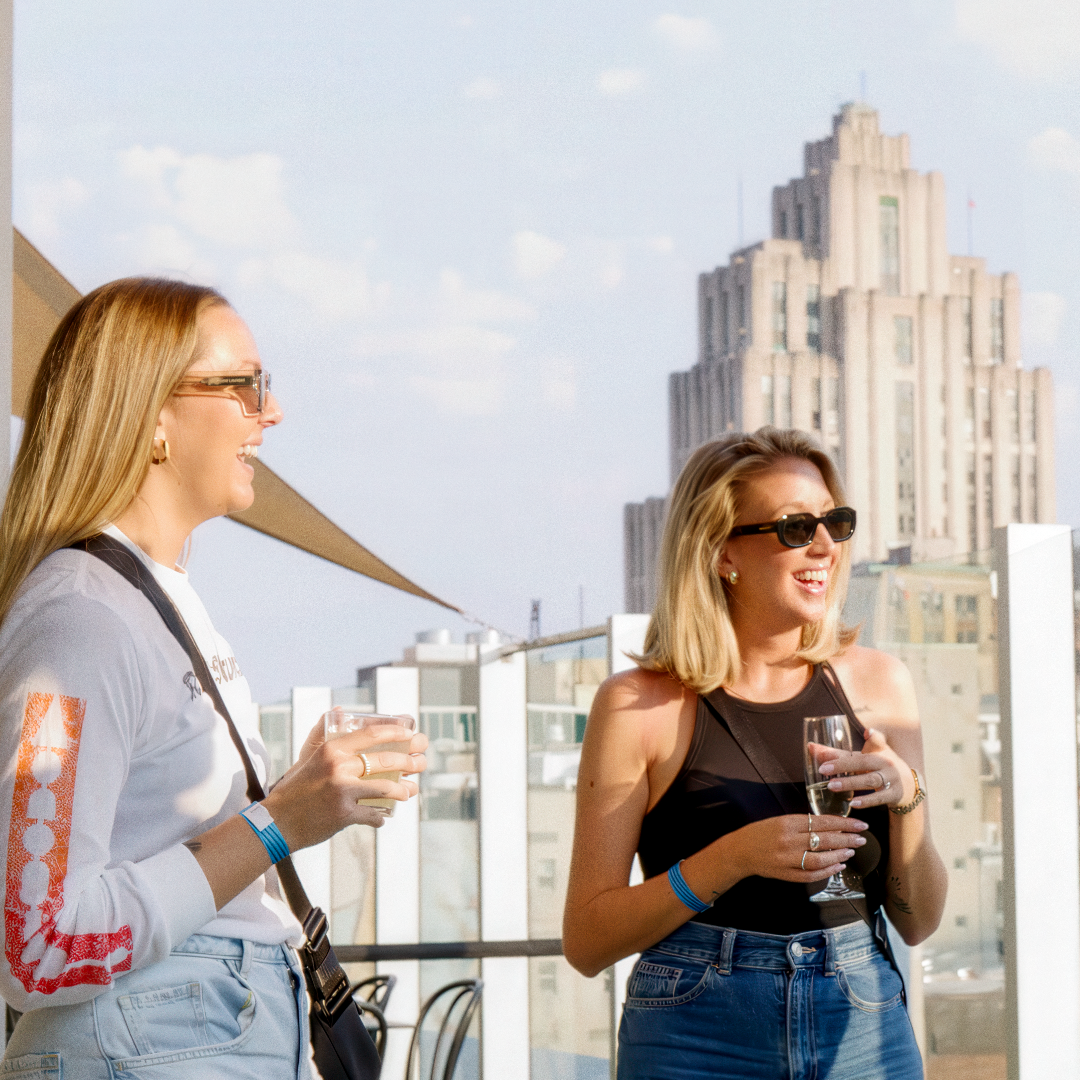 Deux femmes tenant des boissons, discutant sur une terrasse sur le toit à Montréal.